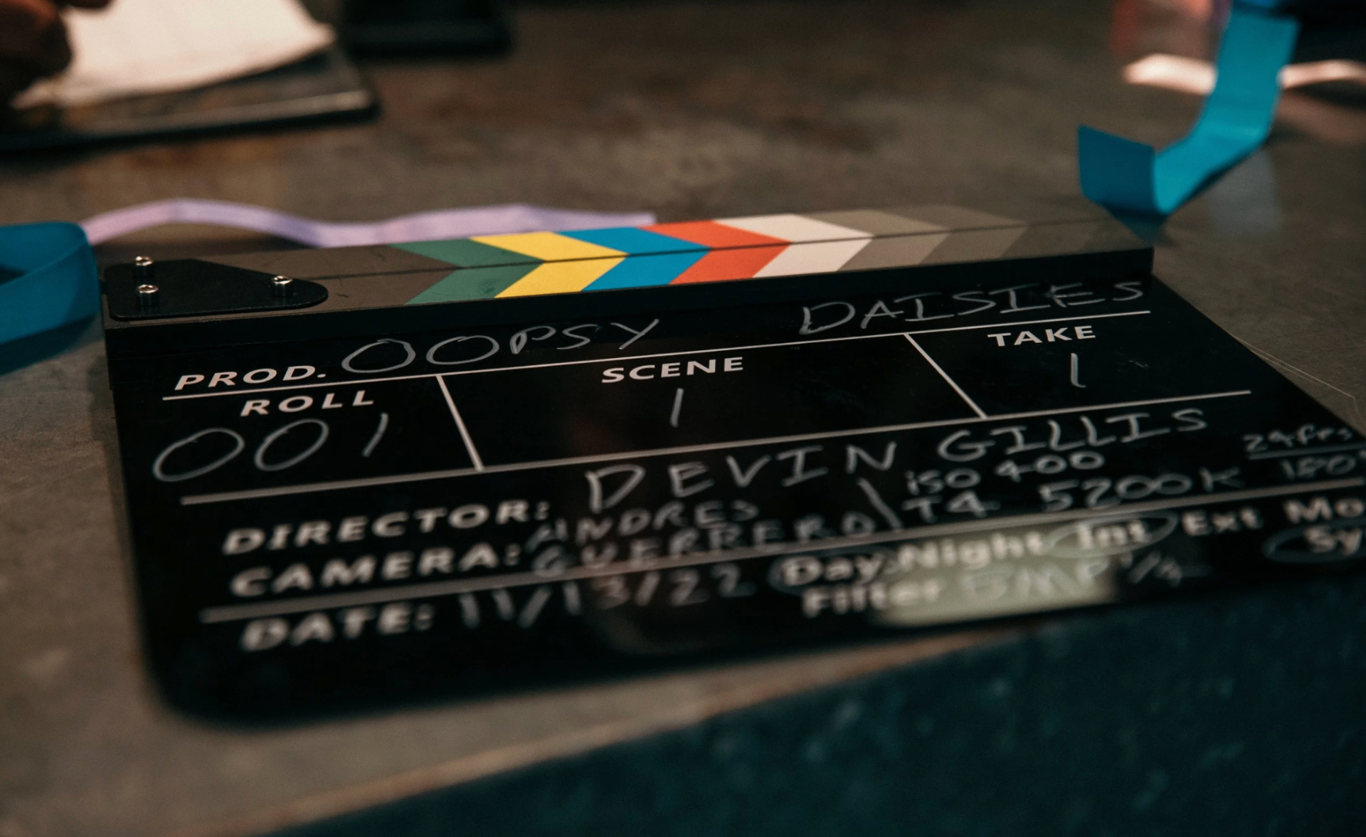 Clapperboard on set misspelled as 'Oopsy Daisies' with film leader and blue ribbon nearby
