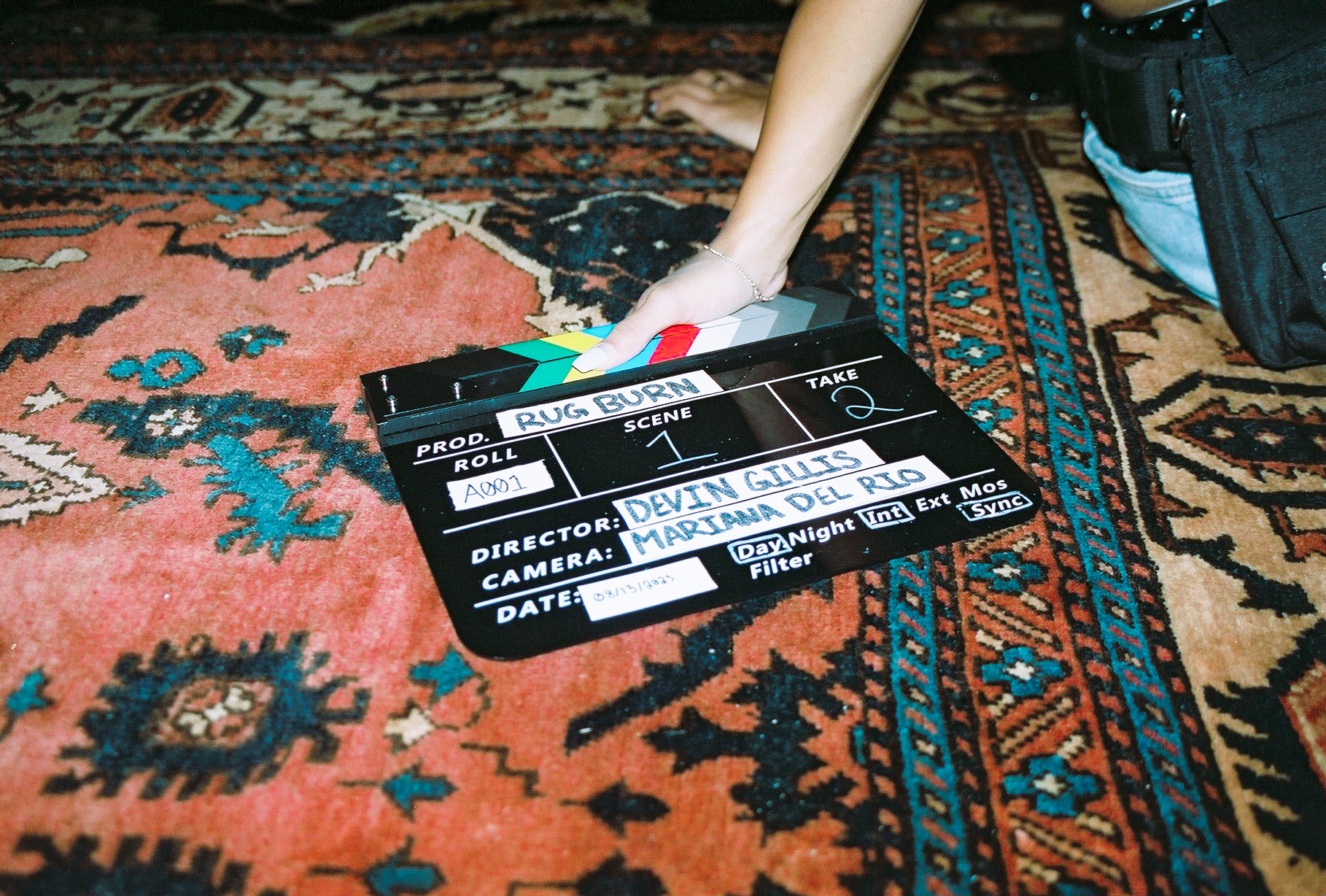 Rug Burn clapperboard resting on a vintage patterned rug on set
