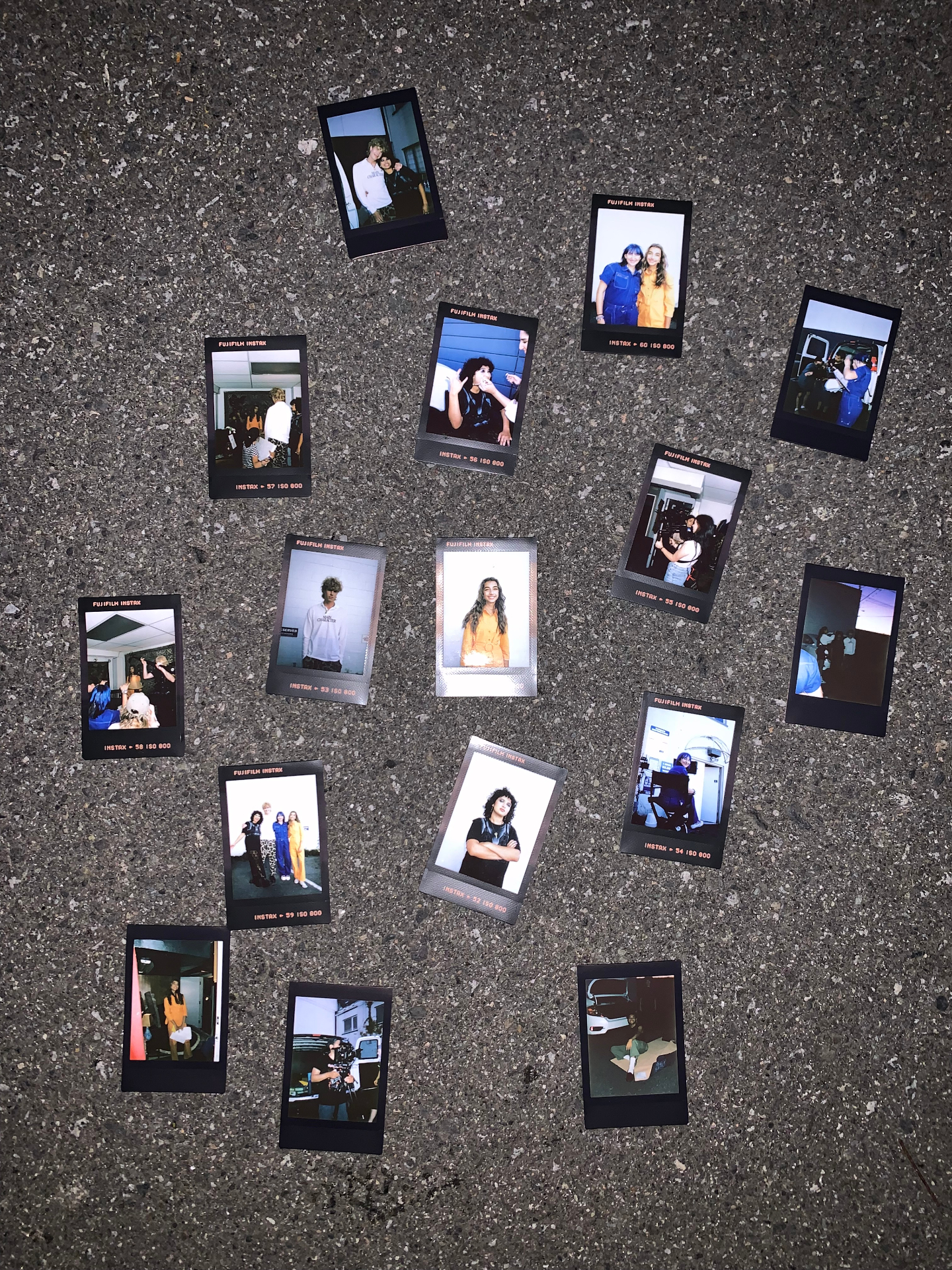 Scattered instant photos from Rug Burn on pavement